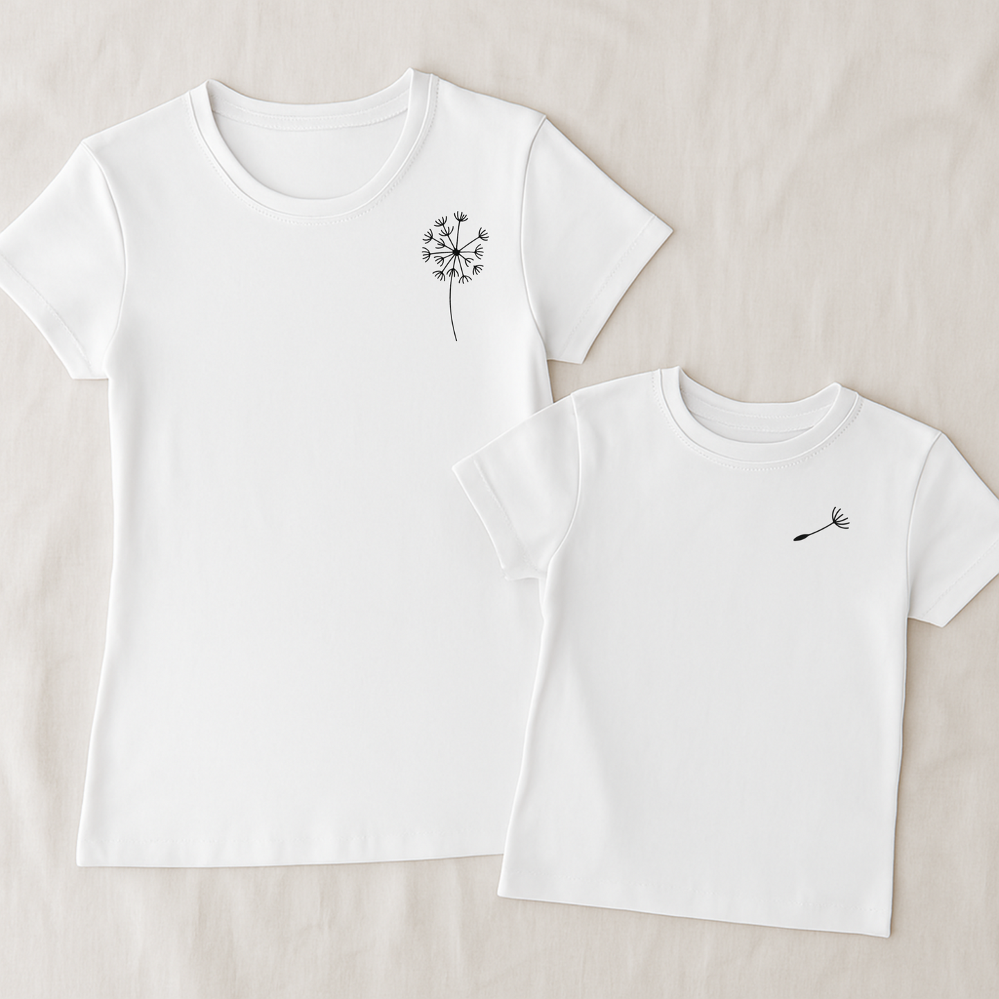 Mama-Kind-Shirt-Set aus Bio-Baumwolle mit Pusteblumen-Design: Auf dem taillierten Mama-Shirt fehlt ein Schirmchen, das auf dem Kind-Shirt einzeln erscheint. Symbol für Liebe, Verbindung und Loslassen. Die Shirts liegen auf natürlichem Hintergrund, modern und nachhaltig inszeniert. Ideal als Muttertagsgeschenk, zur Geburt oder für emotionale Familienmomente. Hier Set in weiß