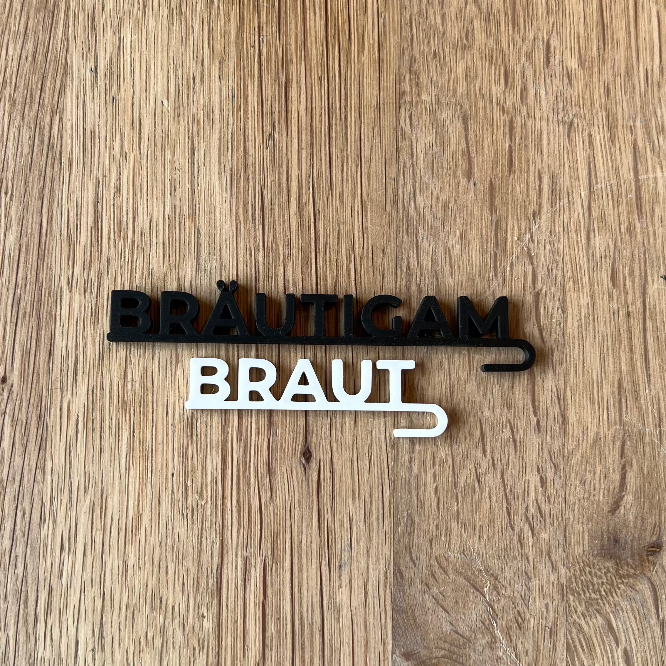 „Nachhaltige 3D-gedruckte Glasanhänger „Braut“ und „Bräutigam“ aus PLA für Hochzeitsgläser dekoriert neben einer Tulpe. Schlichte, elegante Anhänger in Weiß und Schwarz, perfekt für jede Hochzeitsdeko. Diese personalisierten Anhänger verleihen Braut- und Bräutigamsgläsern einen besonderen Touch und passen sich harmonisch verschiedenen Hochzeitsstilen wie Boho, Vintage oder Modern Chic an. Ein umweltfreundliches und elegantes Geschenk zur Hochzeit, das für einen persönlichen Akzent sorgt.“