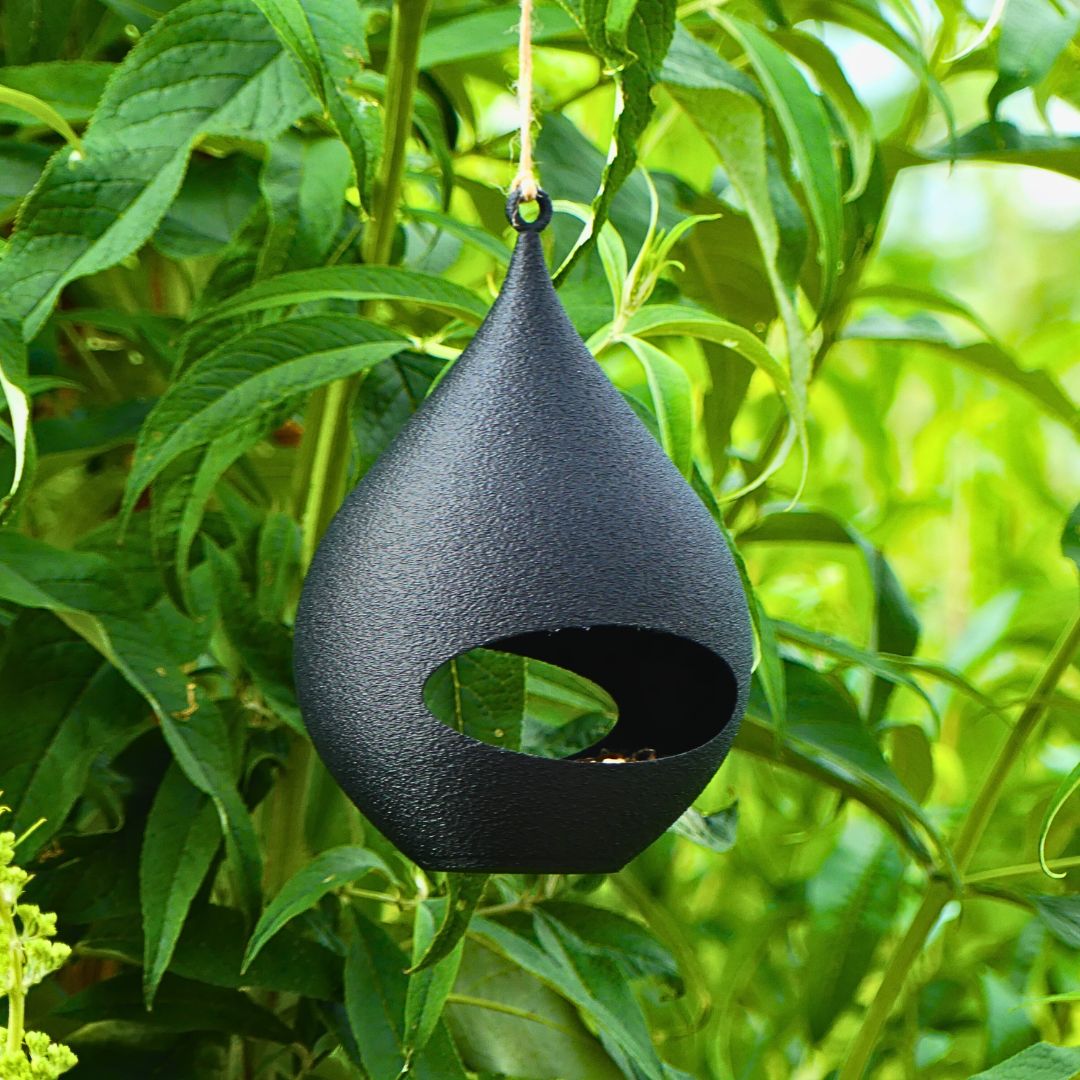 Vogelhäuschen zur Fütterung von Gartenvögeln in schwarz befüllt mit Futter