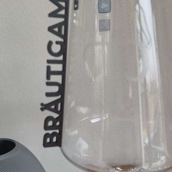 „Nachhaltige 3D-gedruckte Glasanhänger „Braut“ und „Bräutigam“ aus PLA für Hochzeitsgläser dekoriert neben einer Tulpe. Schlichte, elegante Anhänger in Weiß und Schwarz, perfekt für jede Hochzeitsdeko. Diese personalisierten Anhänger verleihen Braut- und Bräutigamsgläsern einen besonderen Touch und passen sich harmonisch verschiedenen Hochzeitsstilen wie Boho, Vintage oder Modern Chic an. Ein umweltfreundliches und elegantes Geschenk zur Hochzeit, das für einen persönlichen Akzent sorgt.“