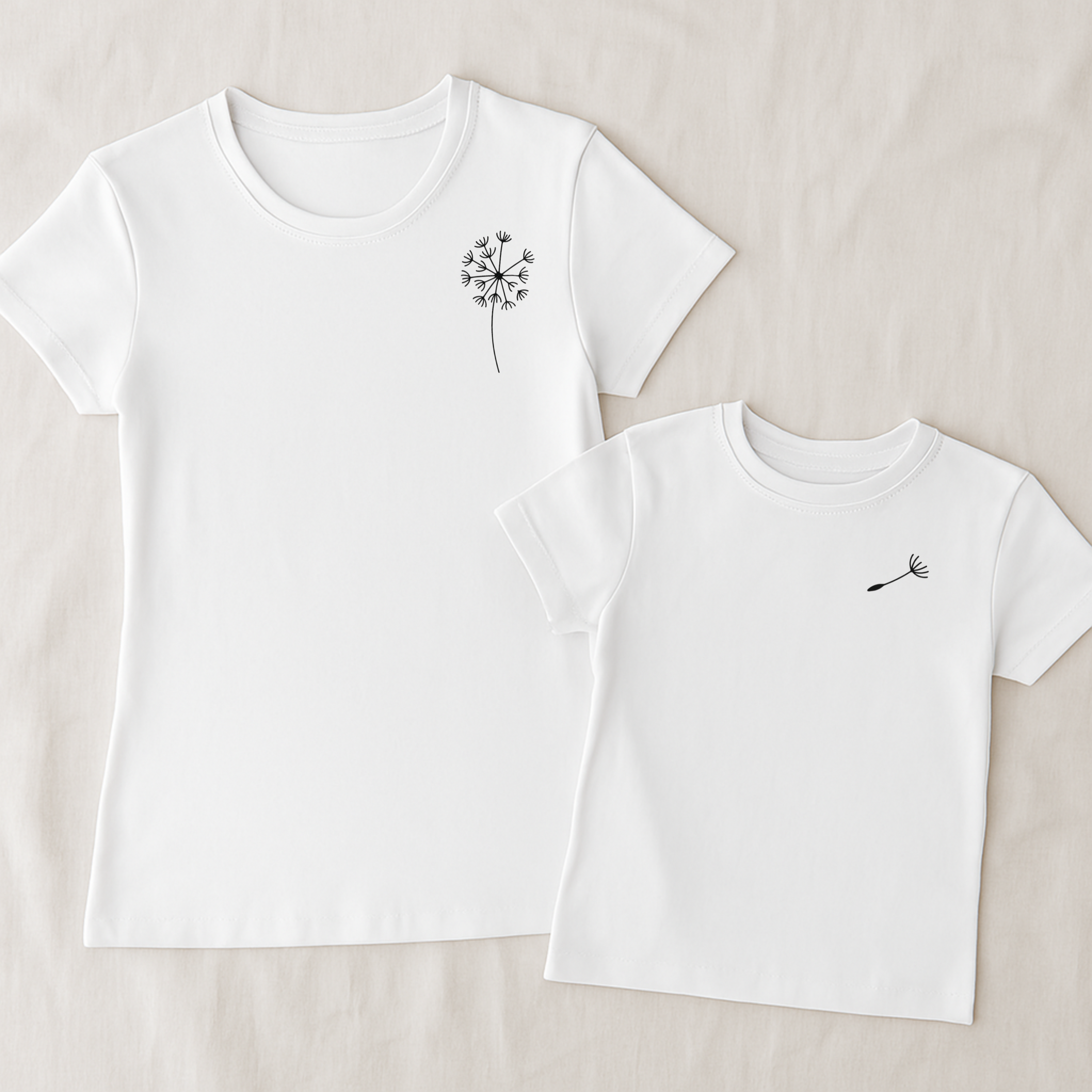 Mama-Kind-Shirt-Set aus Bio-Baumwolle mit Pusteblumen-Design: Auf dem taillierten Mama-Shirt fehlt ein Schirmchen, das auf dem Kind-Shirt einzeln erscheint. Symbol für Liebe, Verbindung und Loslassen. Die Shirts liegen auf natürlichem Hintergrund, modern und nachhaltig inszeniert. Ideal als Muttertagsgeschenk, zur Geburt oder für emotionale Familienmomente. Hier Set in weiß